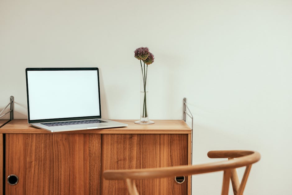Modern minimalist workspace with laptop and plant on wooden desk.